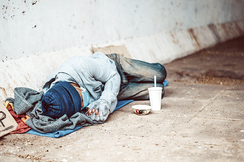 Beggars lying on the side of the street with dirty clothes.
