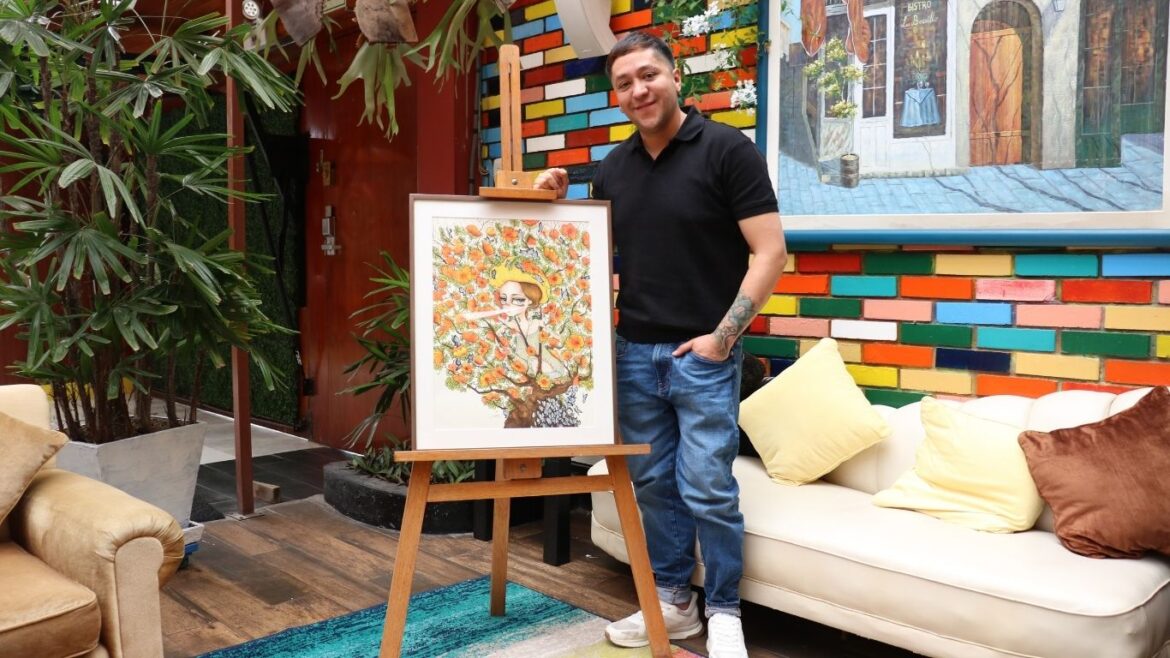 Joan Alfaro junto a una de sus obras de arte de estilo surrealista y colores neón.